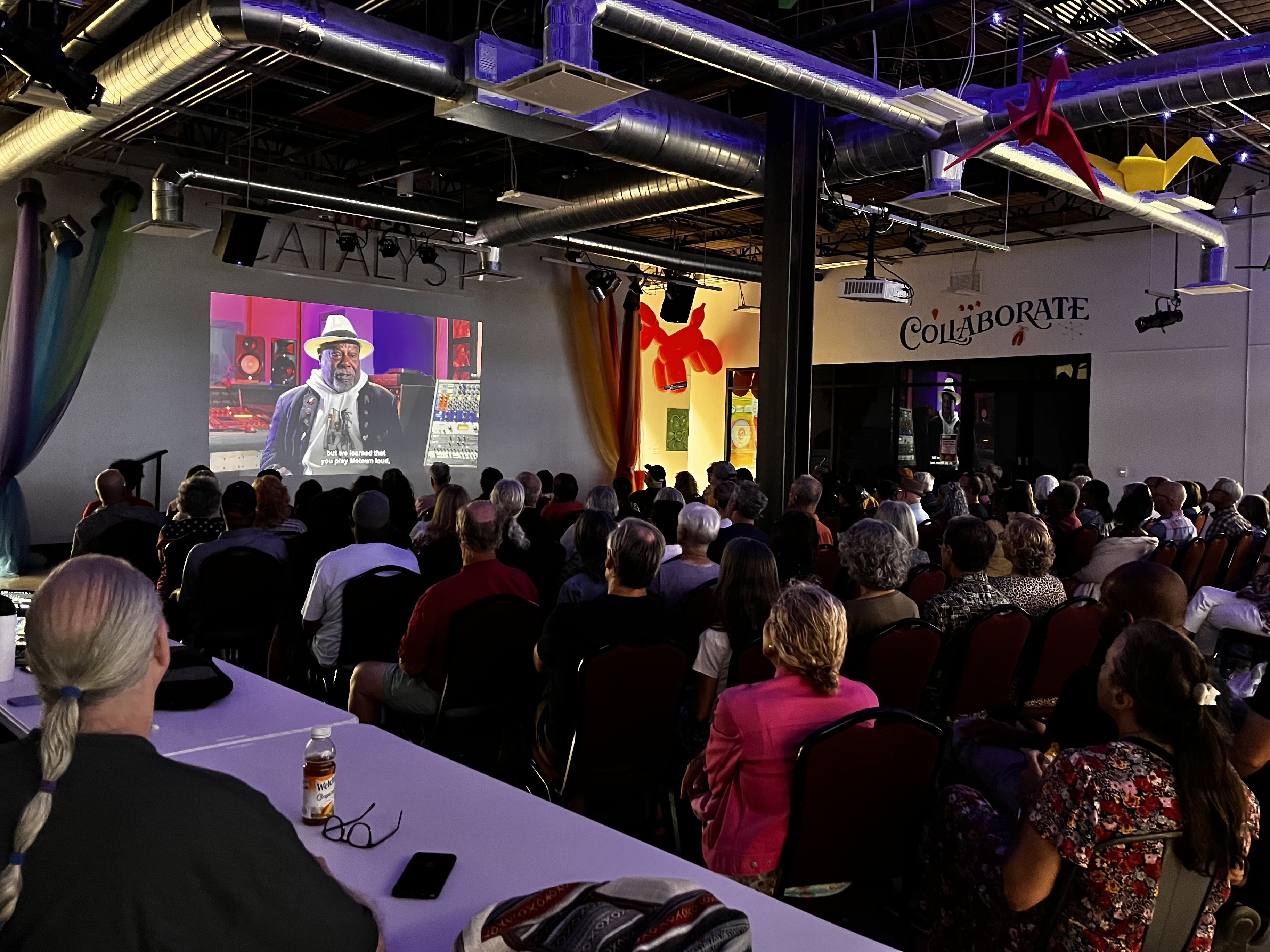 Image of a large audience gathered in a dark room, watching a film screening.