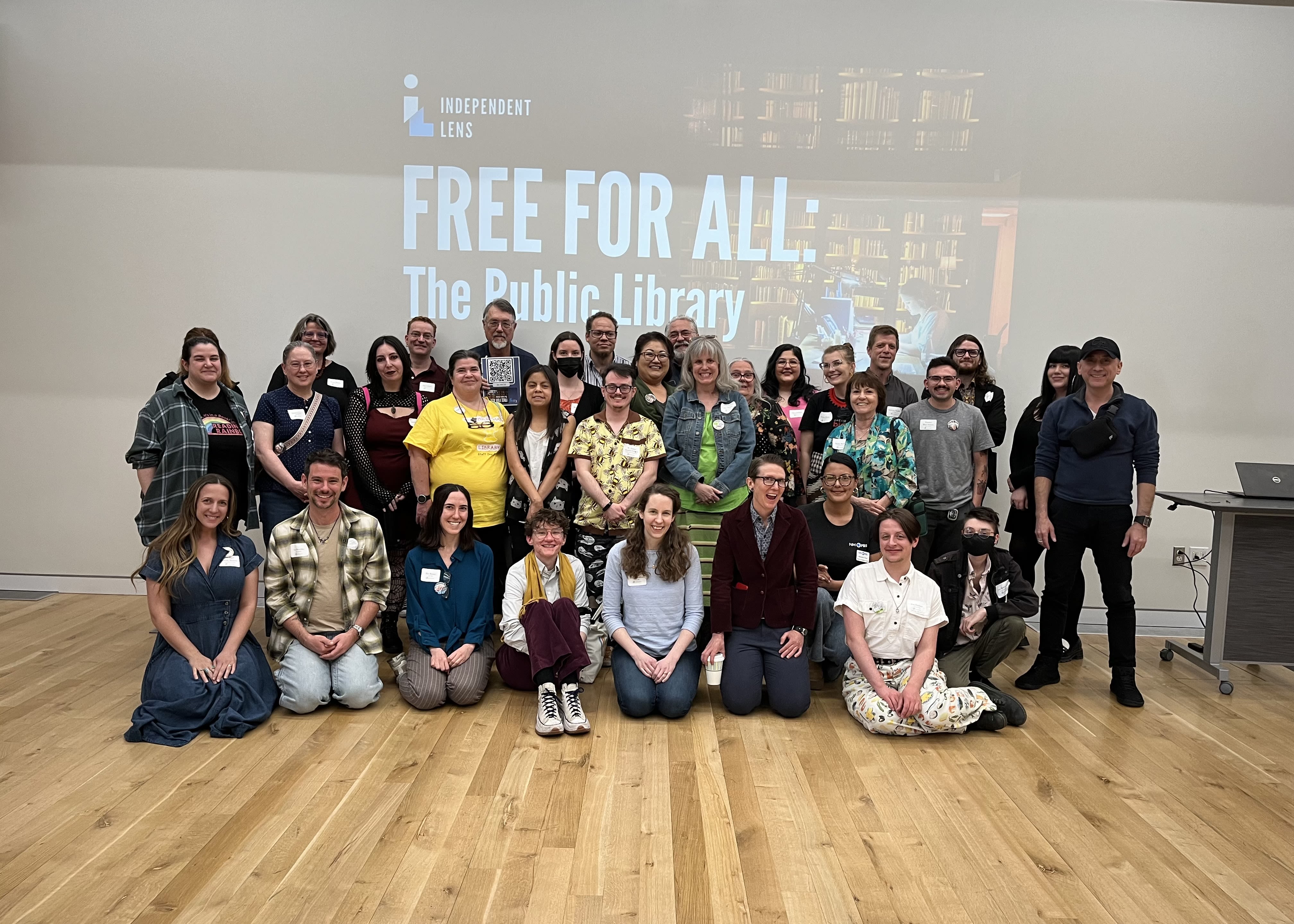Image of about 30 people posing in front of a large screen.